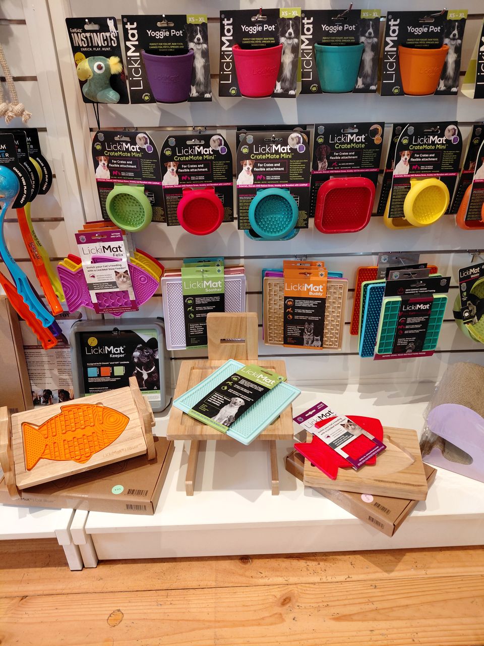 A wall of colourful LickiMat lick mats and wooden holders at For Pets Sake SA